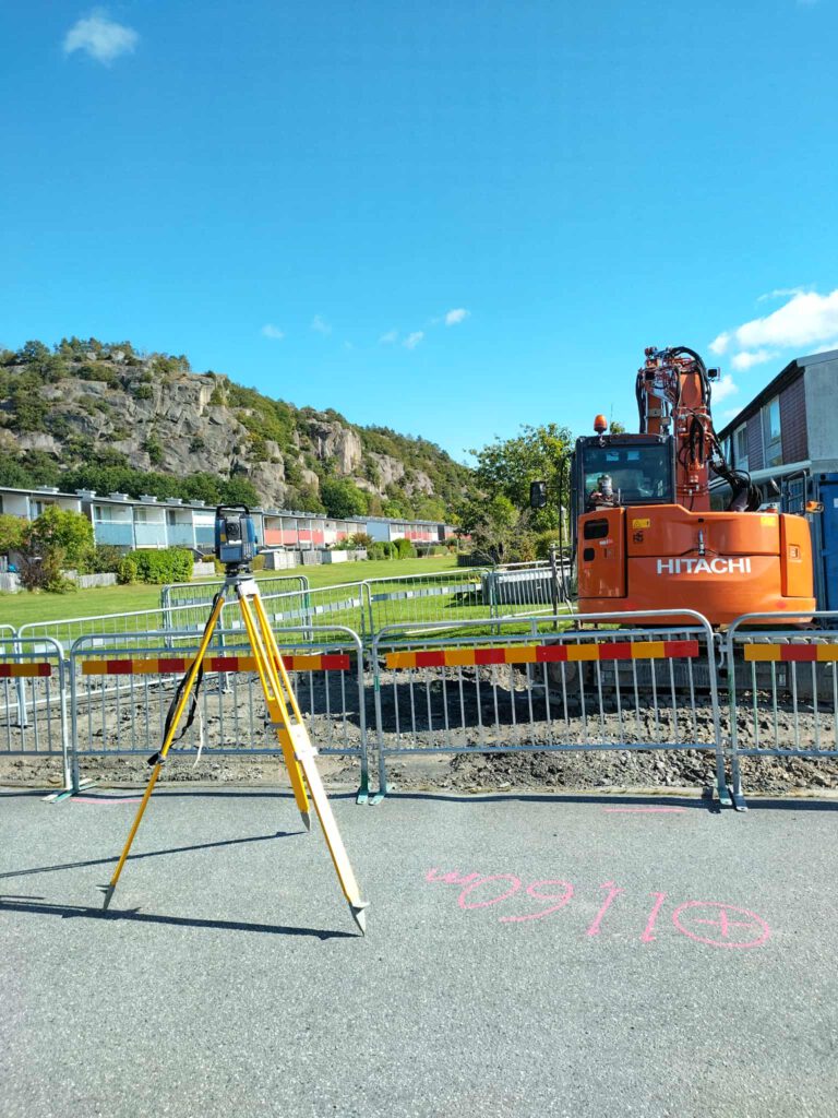 En grävmaskin uppställd med totalstation. En höjdfix avsätts för maskinstyrning.