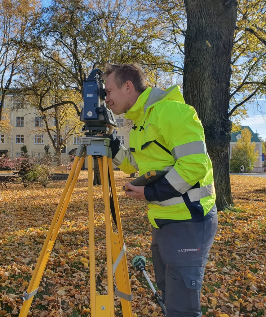 En mätningstekniker tittar genom en totalstation vid en utsättning i Eksjö